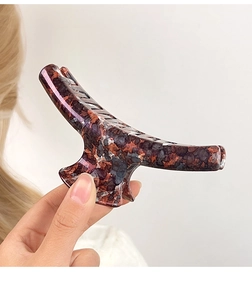 Macro detail of large tortoise shell hair claw clip with glossy leopard print finish