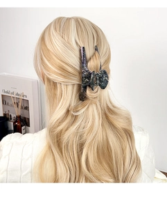 Detail of a large marbled resin shark hair claw clip styled on long blonde hair
