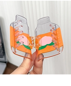 Gros plan d'une pince à cheveux transparente avec illustration de pêche et ressort en métal
