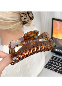 Macro detail of tortoiseshell hair claw clip with golden lettering and strong grip design