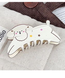 Detail of cute cream puppy hair claw clip with colorful stars on textured fabric