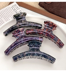 Detail of four retro marble ink texture large hair claws on a decorative white ceramic plate