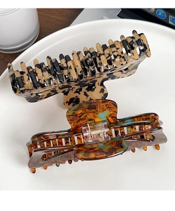Detail of oversized tortoiseshell hair claw clips on a white ceramic plate