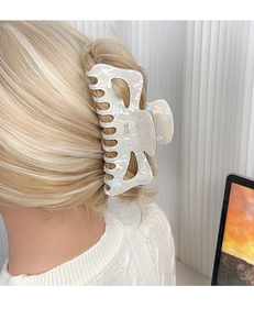 Oversized pearlized bow hair claw clip styled on blonde wavy hair in office setting