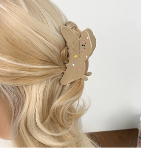 Detailed view of a cute khaki dog-shaped hair claw clip with colorful star patterns
