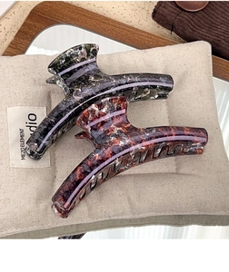 Detailed view of large marble texture hair claws in dark grey and reddish brown colors