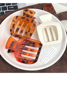 Trois pinces à cheveux mates en écaille et crème sur une assiette en céramique blanche