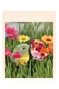 Detailed view of two colorful bird-shaped hair claw clips with glitter acetate finish
