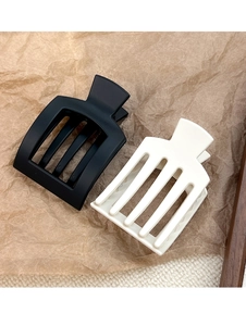 Detail of matte rectangular hair claws in black and cream white with hollow design