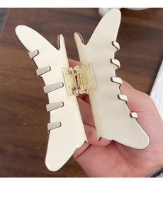 Detail view of the large cream butterfly hair claw clip with golden metal spring