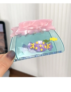 Détail d'une grande pince à cheveux en acétate bleu avec bonbons 3D et bordure rose