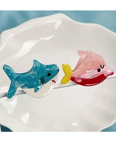 Details von blauen Hai- und rosa Fisch-Haarklammern aus marmoriertem Acetat auf Keramik