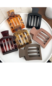 Set of six large matte square hair claws in assorted colors on a minimalist ceramic plate
