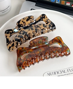 Detail of two tortoise shell hair claws in cream and brown on a white tray