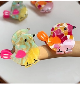 Macro shot of colorful bird hair clips with marble texture and mosaic patterns
