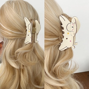Cute cream puppy hair claw with colorful stars shown on blonde wavy hair