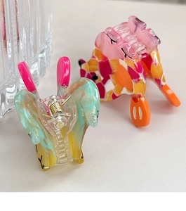 Detail shot of colorful acetate fish-shaped hair claw clips with gold metal springs