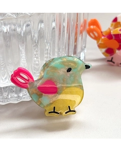 Detailed macro view of acetate bird hair clip with colorful marble pattern and gold glitter