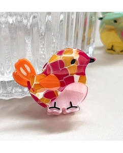 Close-up of bird hair clip with colorful acetate mosaic patterns and glitter accents