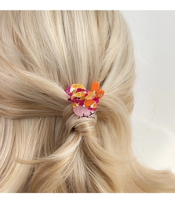 Detailed view of colorful acetate bird hair clip styling on golden blonde hair