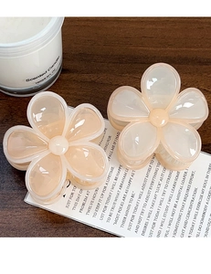Dettaglio macro di due mollette per capelli a fiore di plumeria su sfondo di legno caldo
