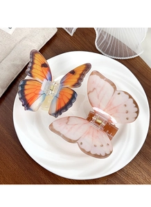 Gros plan de pinces à cheveux papillon orange et rose posées sur une assiette blanche
