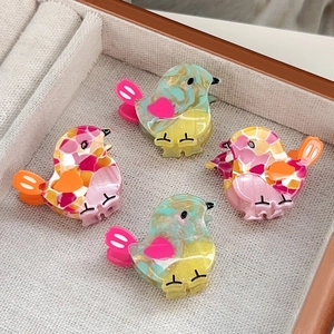 Set of four colorful bird hair clips in marble and mosaic acetate finish on display tray