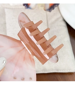 Gros plan détaillé sur une pince à cheveux papillon en acétate rose marbré avec texture