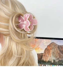 Dettaglio di un fermaglio per capelli a fiore rosa su capelli biondi mossi
