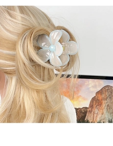 Dettaglio di un fermaglio per capelli a forma di plumeria blu su uno chignon biondo