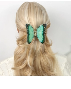 Vue détaillée de la pince à cheveux papillon avec dégradé bleu-vert dans les cheveux