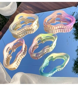 Détail de cinq pinces à cheveux ondulées colorées avec finition nacrée sur un miroir
