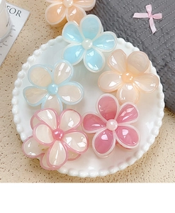 Dettaglio di fermacapelli a forma di fiore di plumeria in colori pastello macaron