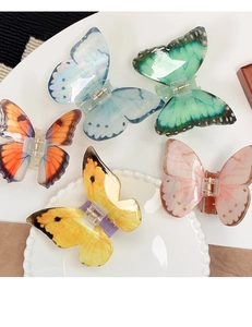 Vue détaillée de dessus des pinces à cheveux papillon multicolores sur un plateau blanc