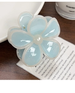 Dettaglio molletta per capelli a forma di fiore azzurro con finitura lucida e bordi bianchi
