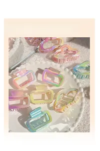 Close-up of iridescent gradient hair claw clips displayed on a white ceramic plate
