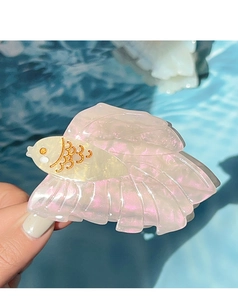 Detailaufnahme einer perlmuttfarbenen Fisch-Haarklammer mit irisierenden Schuppen-Details