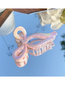 Pince à cheveux rose irisée en forme de nœud avec finition nacrée sur un miroir