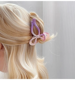 Gros plan d'une pince à cheveux papillon nacrée dégradée sur des cheveux blonds ondulés