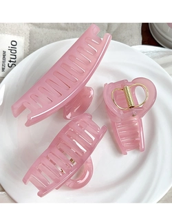 Detailed set of translucent pink hair claws in various shapes on a ceramic dish