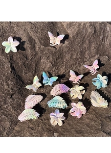 Iridescent butterfly and plumeria flower hair claws set on a natural stone surface