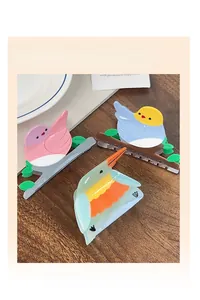 Tres pinzas para el cabello con forma de pájaro en rosa, azul y verde sobre madera