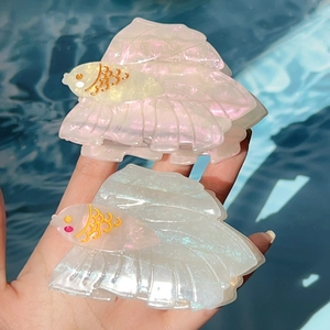 Schillernde Haarklammern aus Acetat in Goldfischform mit Glitzereffekt am Wasser