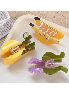 Detailed view of banana and fruit shaped acetate hair claws on a cream tray display