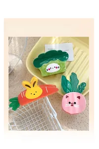 Three cute vegetable acetate hair claws shown on a yellow plate and white basket