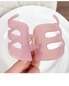 Close-up of a pink jelly hair claw clip with golden metal spring for daily hairstyling