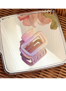 Macro shot of square gradient hair claw with pearlescent finish on a mirror base