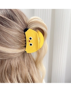 Banana shaped hair claw clip in bright yellow with cartoon face on blonde hair
