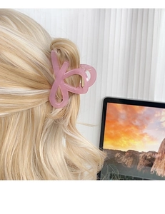 Pink translucent resin hair claw clip shown in a side-back view on long blonde hair