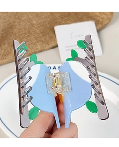 Detalle de pinza para el pelo de acetato azul y blanco con diseño de hoja y muelle